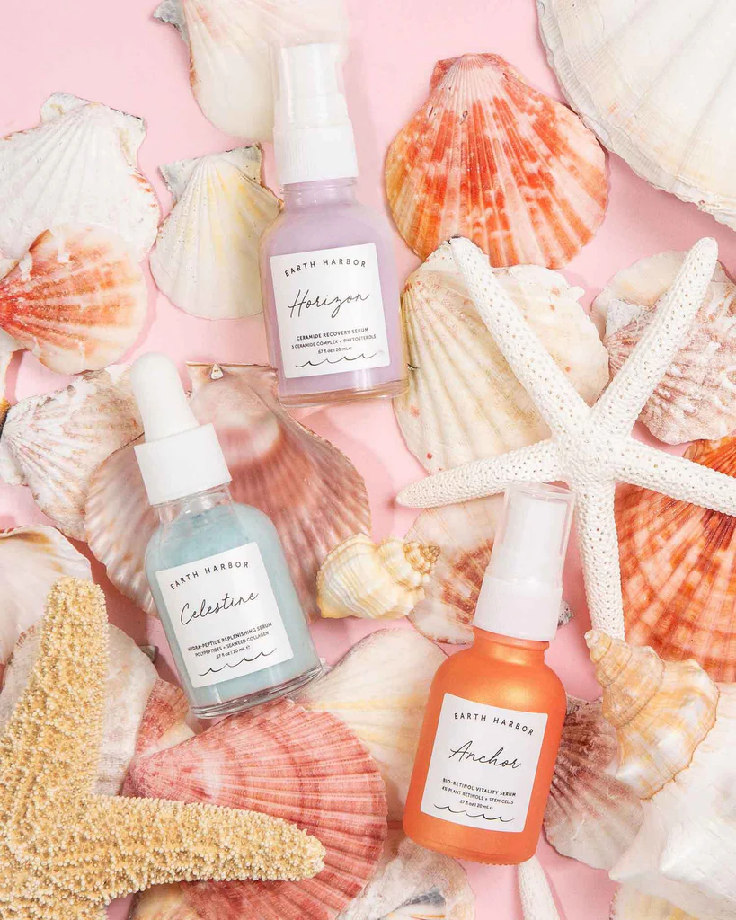 Earth Harbor skincare bottles arranged on
seashells and starfish on a pink background​