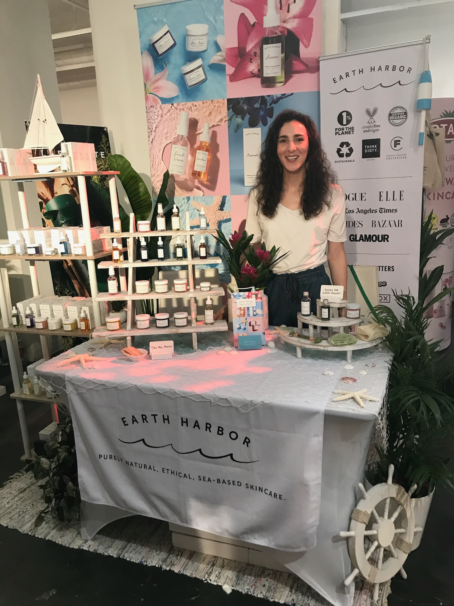 Woman standing at a skincare display
booth with products arranged on shelves.​