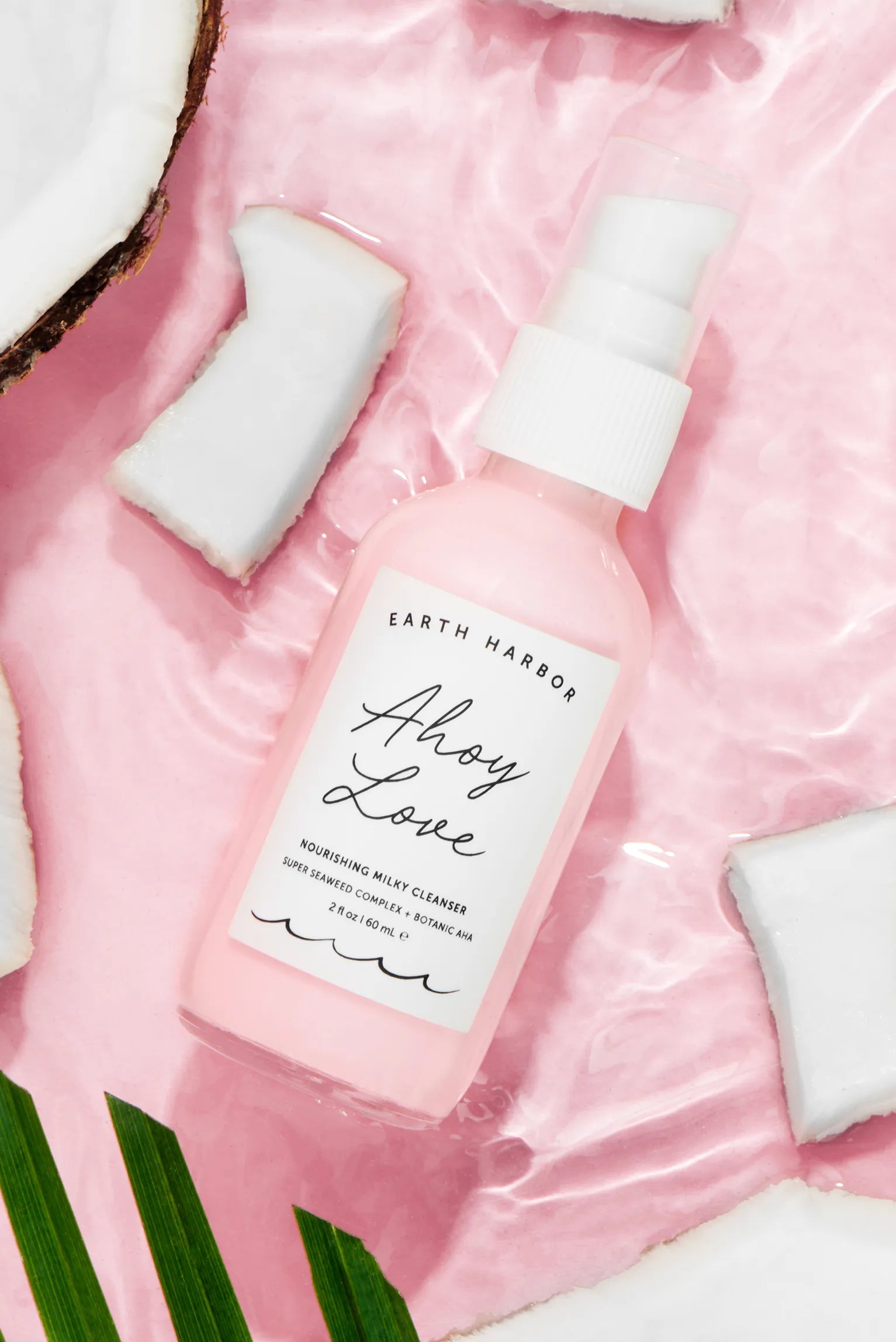 arth Harbor Ahoy Love cleanser bottle
lying flat on rippling pink water with
coconut chunks.​