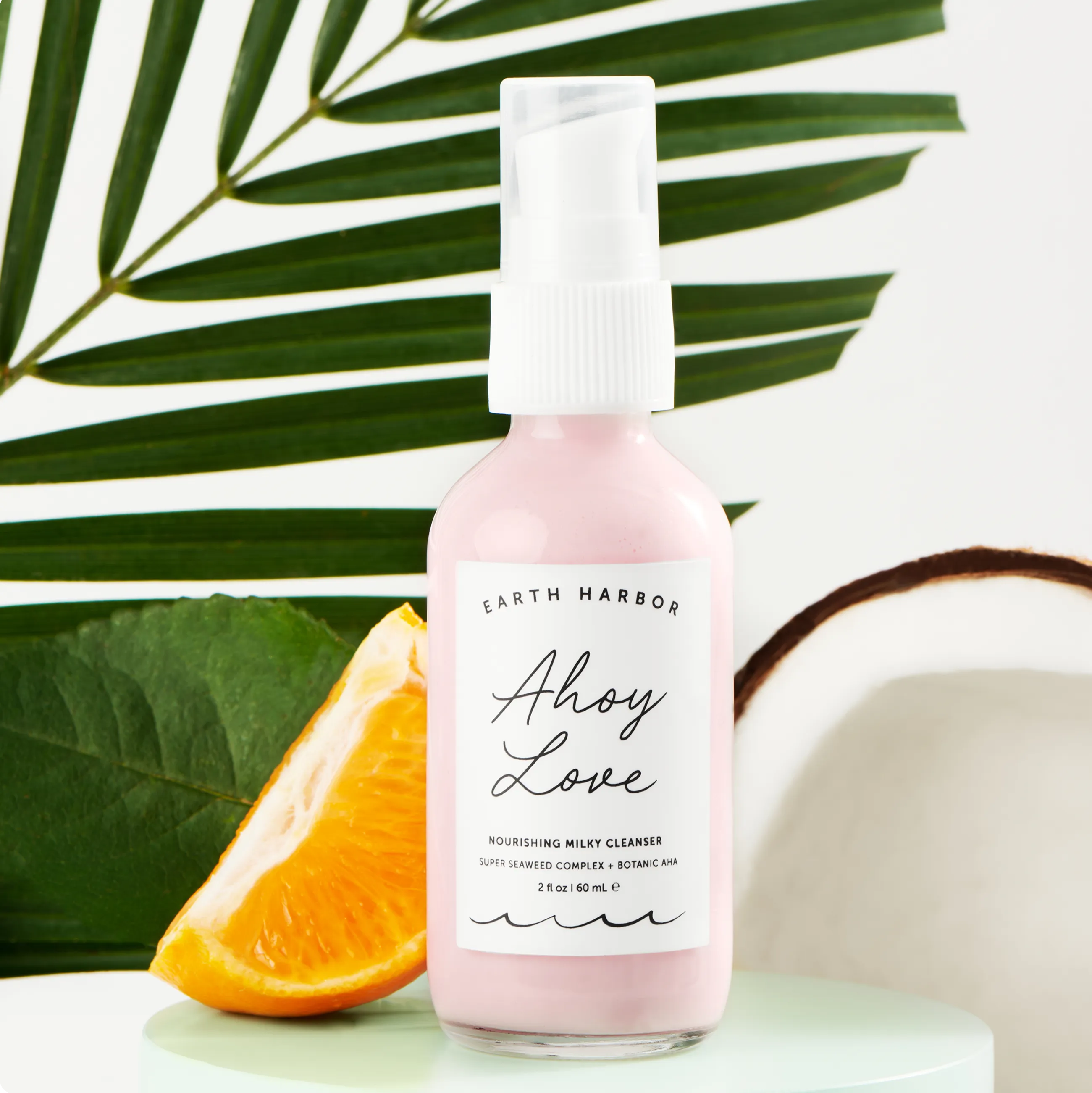 Close-up of Earth Harbor Ahoy Love
Nourishing Milky Cleanser with an orange
slice and coconut.​