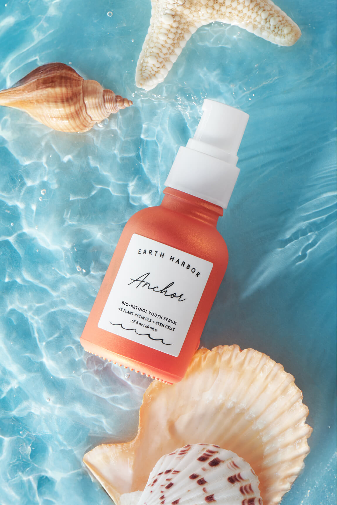 Earth Harbor Anchor serum bottle in clear
blue water with a starfish and seashells.​