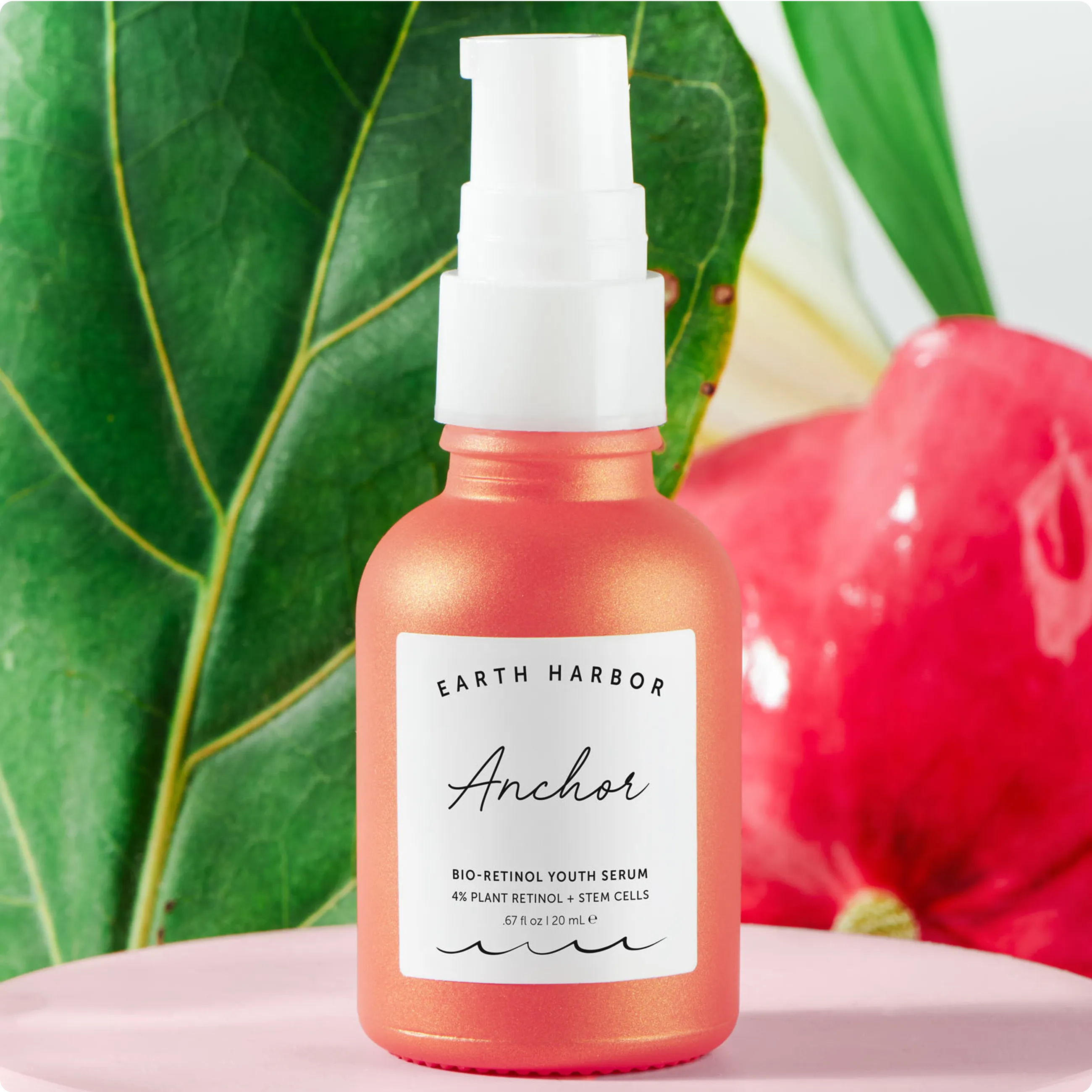 An orange Earth Harbor Anchor serum
bottle in front of a large green leaf and a
glossy pink background.​