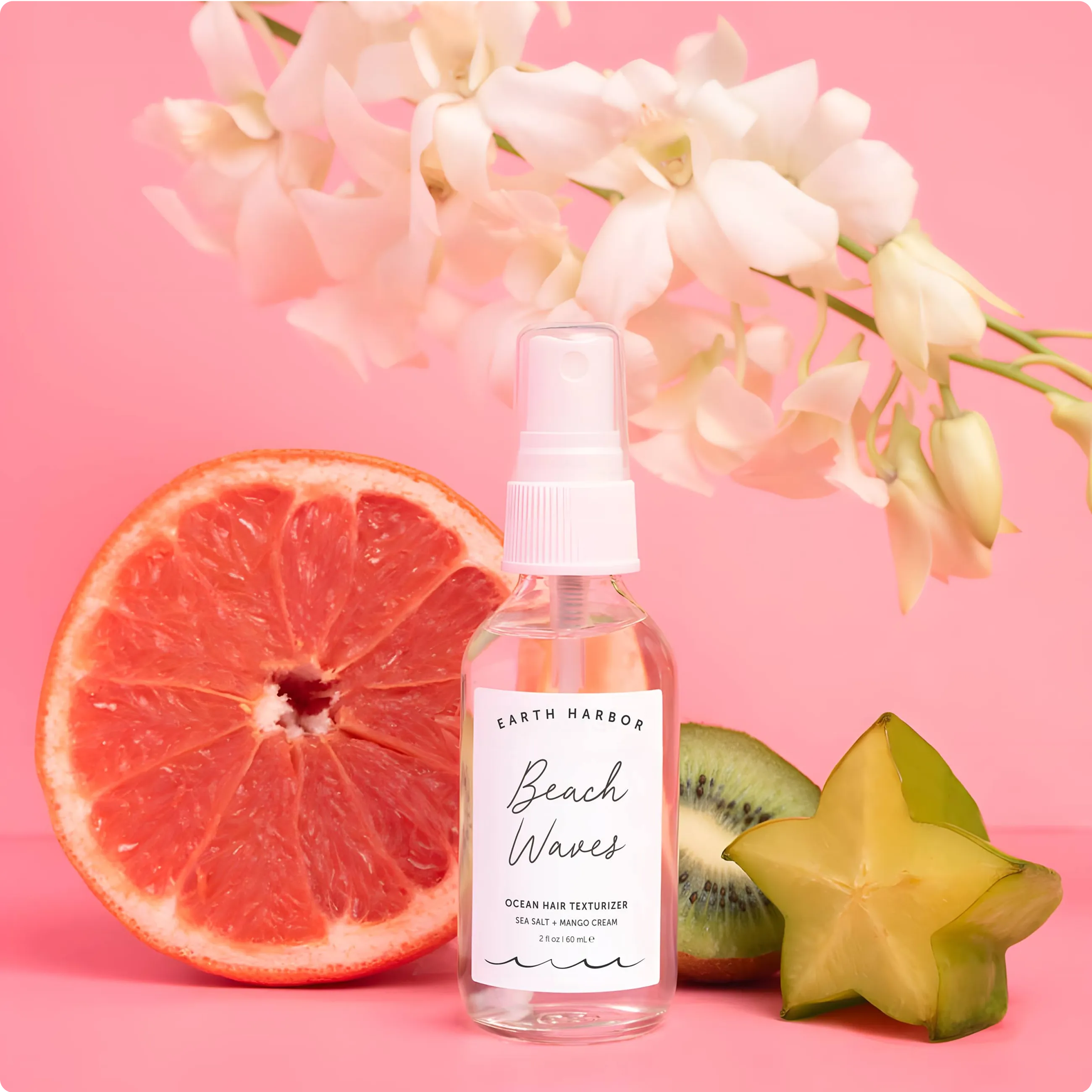 Earth Harbor Beach Waves spray bottle in
front of a sliced grapefruit, starfruit, kiwi,
and white orchid flowers.​