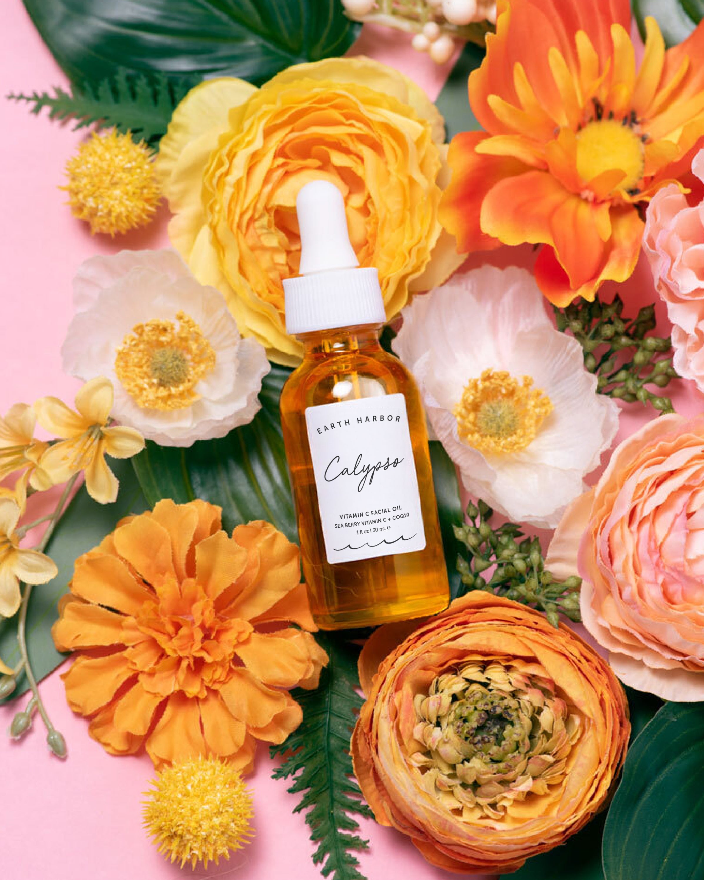 Bottle of Calypso skincare serum surrounded by colorful flowers on a pink background