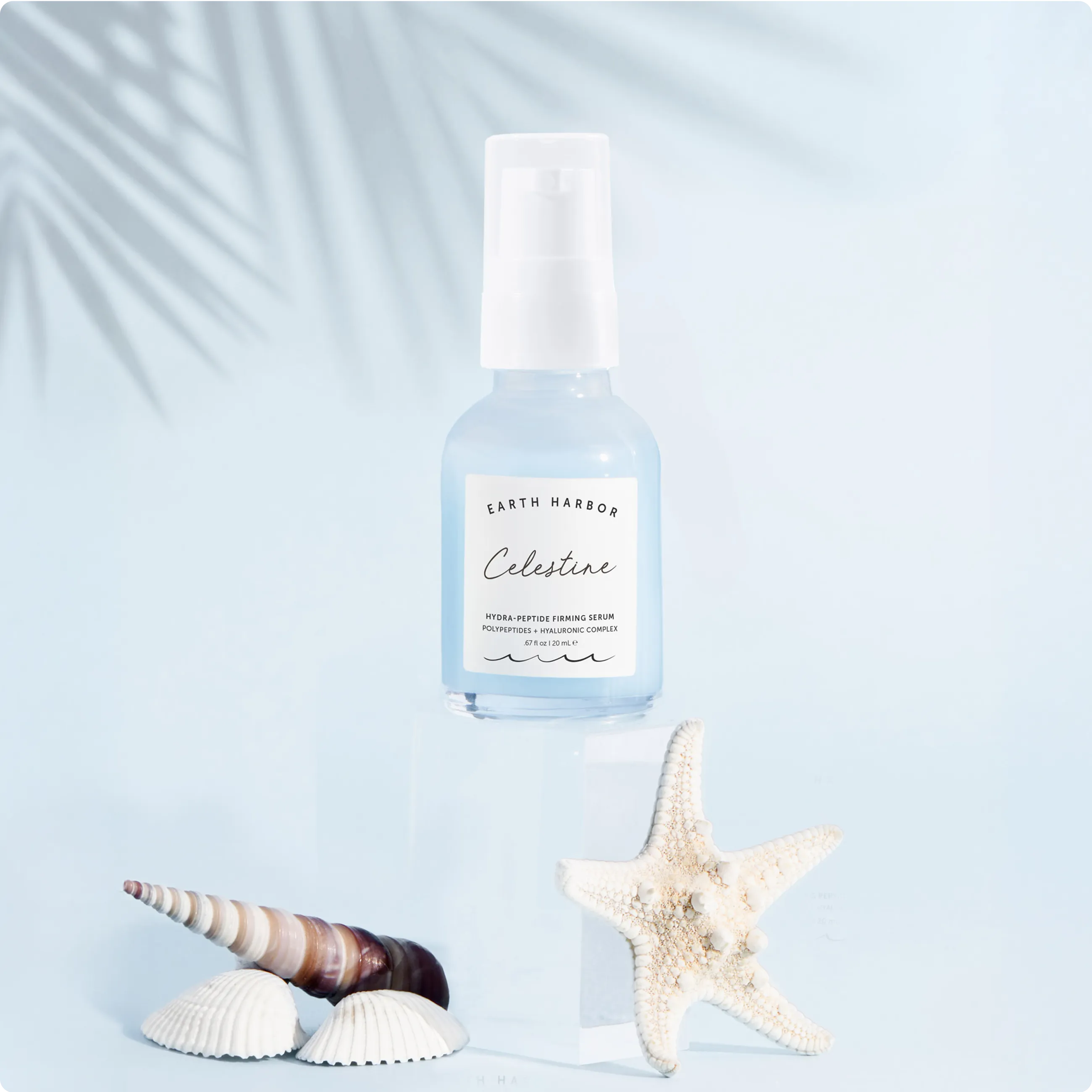 Earth Harbor Celestine serum bottle on a
light blue background with a starfish and
seashell.​