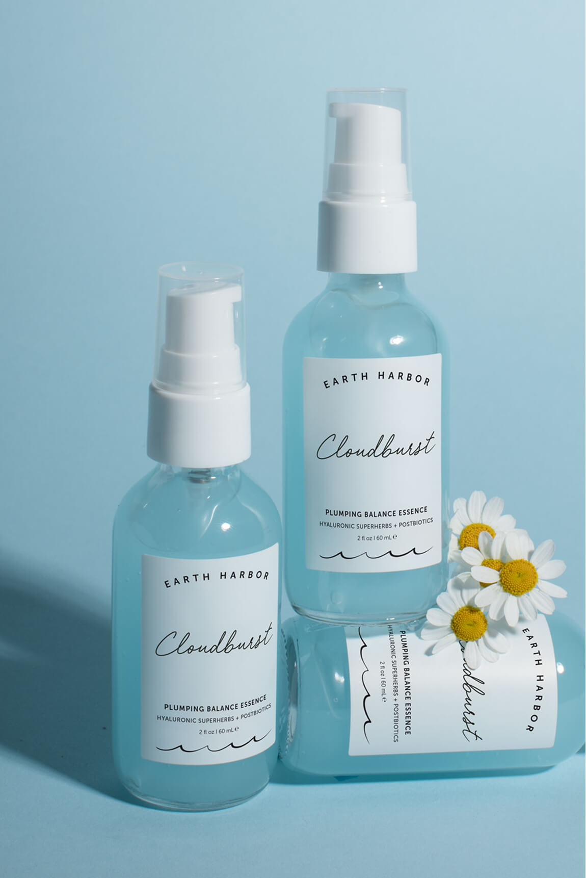 Three blue bottles of Earth Harbor
Cloudburst essence arranged on a blue
background with small white flowers.​