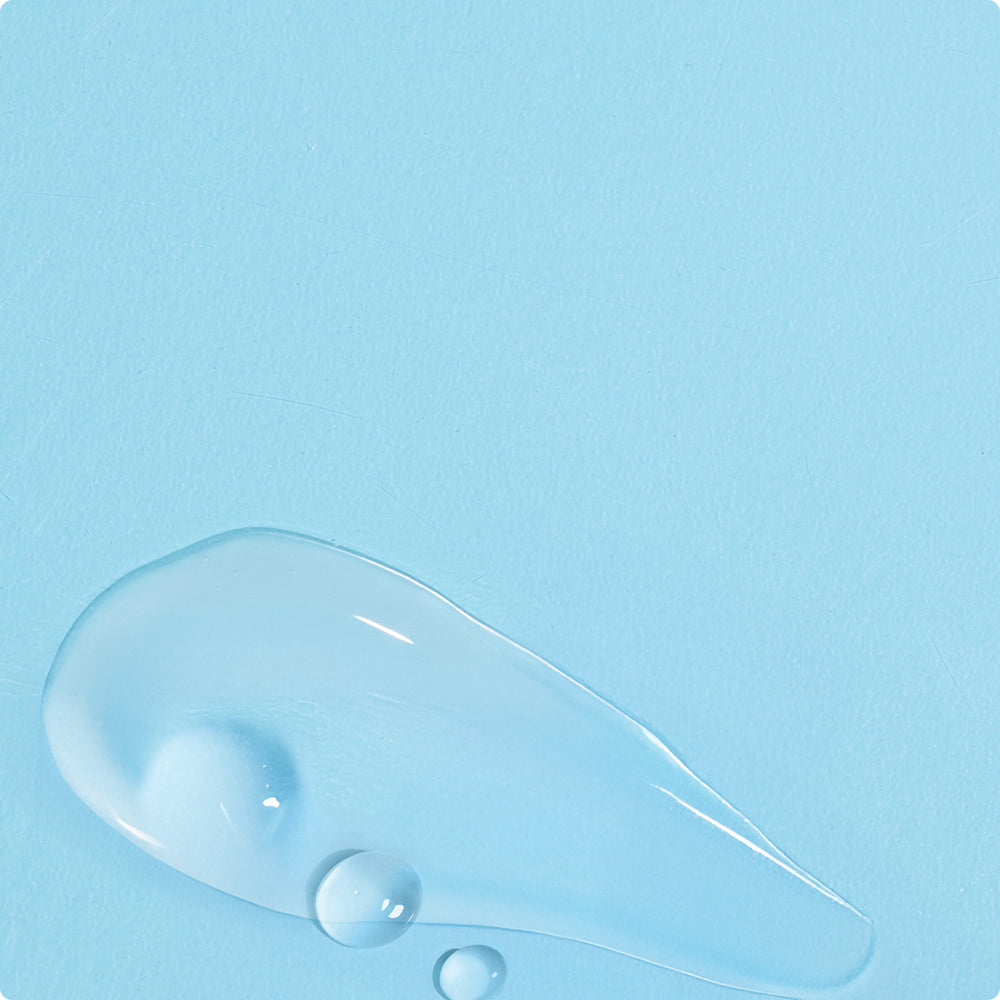 Clear, glossy skincare gel smear with small droplets
on a light blue textured surface.​