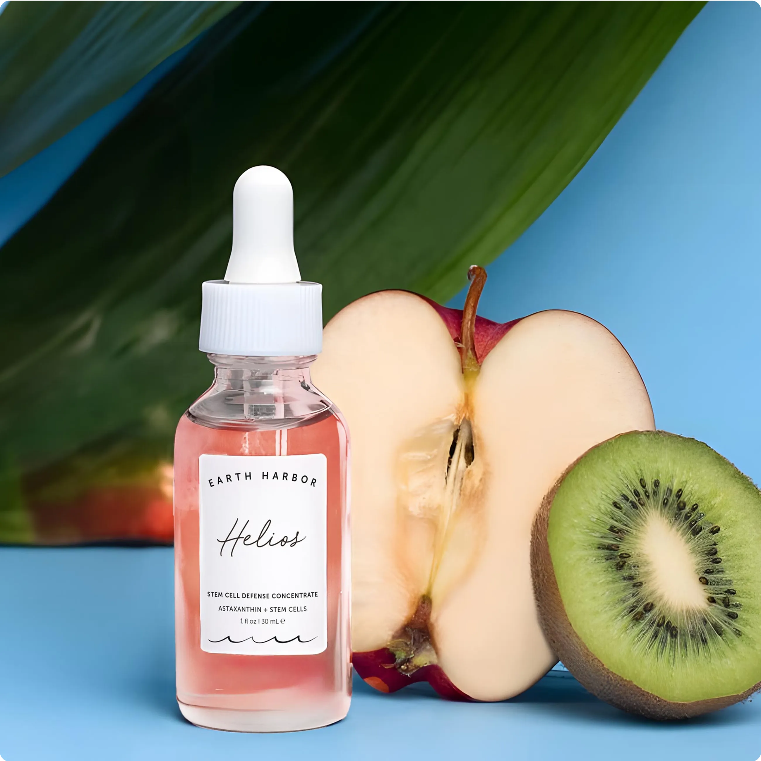 Earth Harbor Helios concentrate bottle on
a blue background next to a sliced apple
half and a sliced kiwi.​
