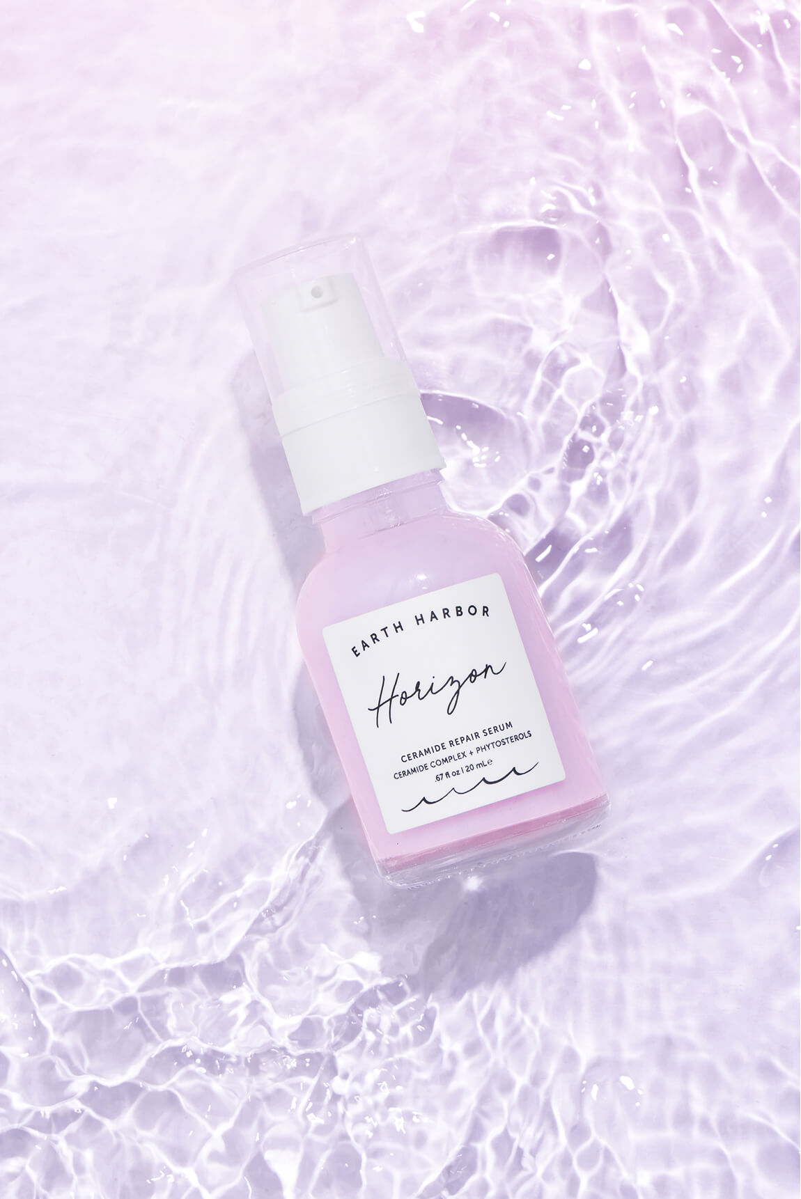 Earth Harbor Horizon serum bottle floating
in light purple, rippled water.​