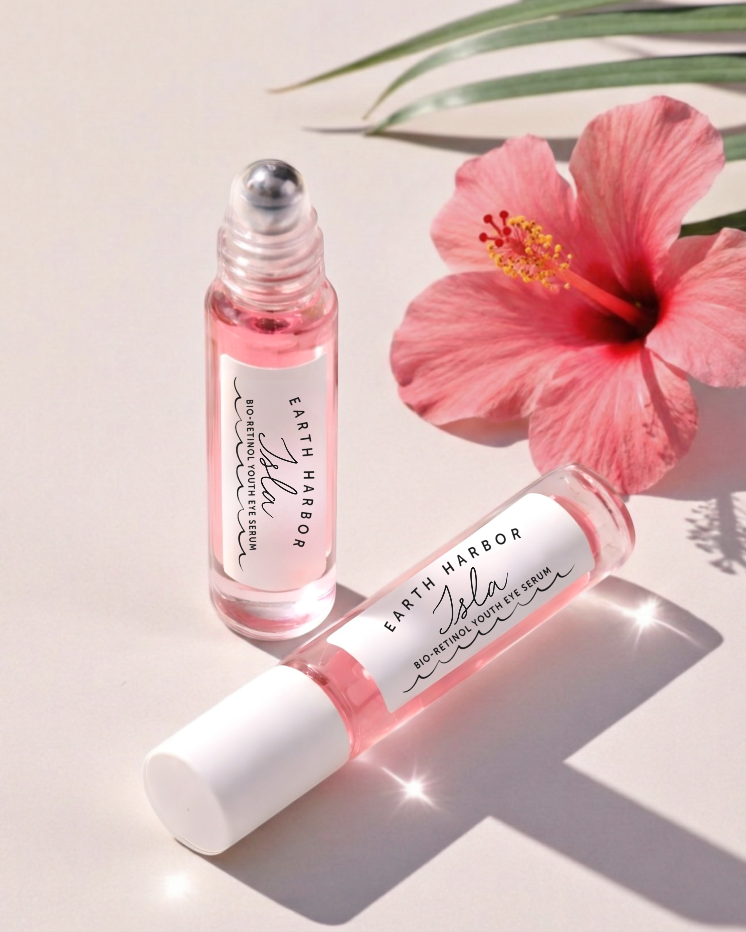 Pink Isla serum bottles displayed with a
hibiscus flower on a light surface