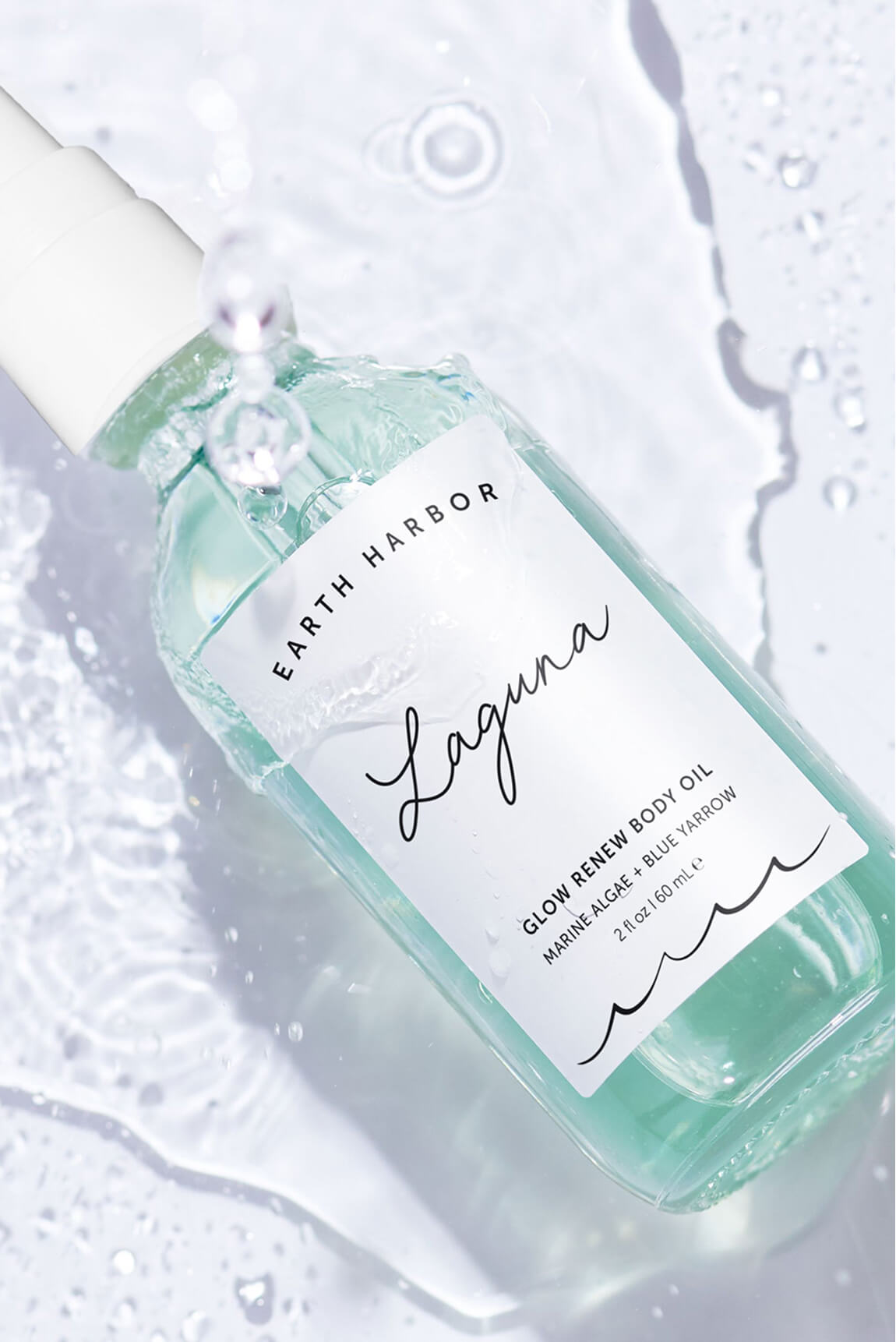 A bottle of Earth Harbor Laguna body oil
splashing into clear water ripples.​