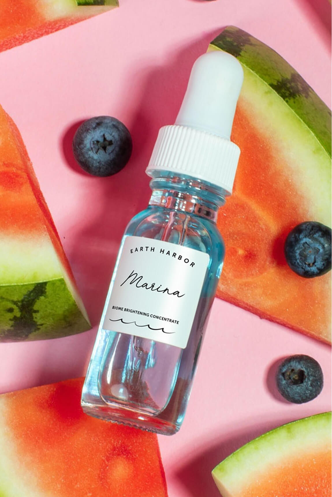 Earth Harbor Marina concentrate bottle on
a pink background surrounded by
watermelon slices and blueberries.​
