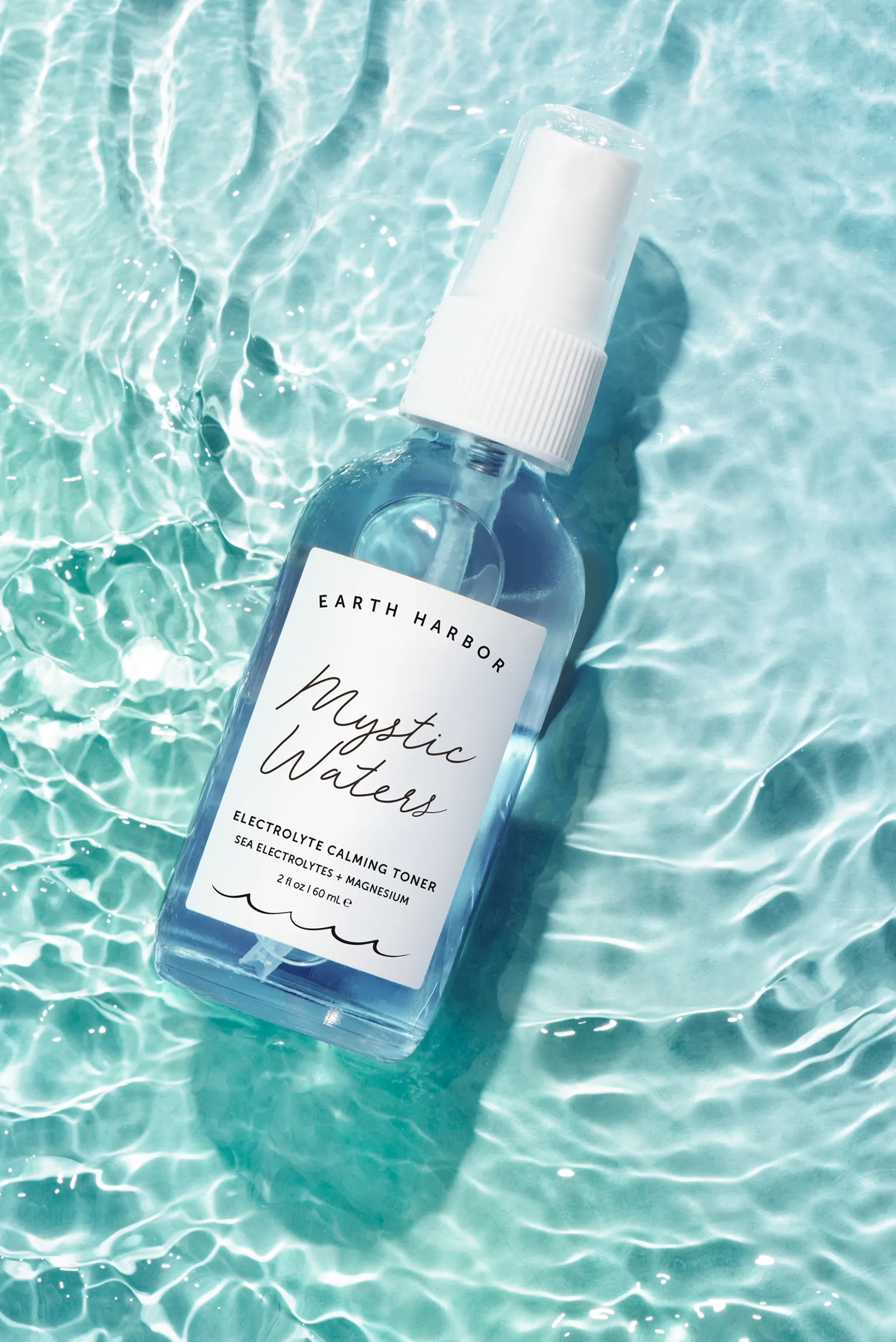 Earth Harbor Mystic Waters toner bottle
resting in rippling clear water.​