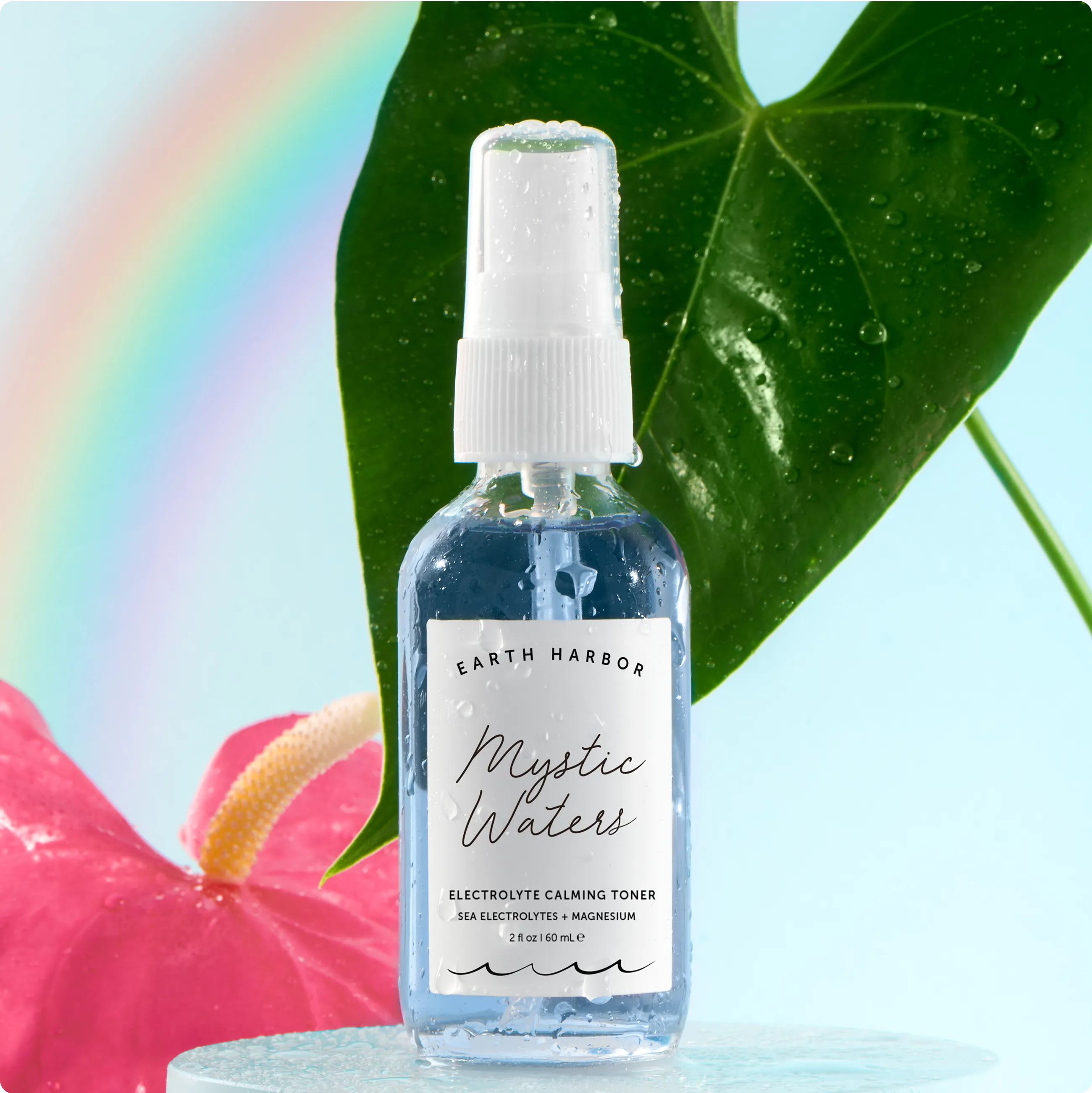 Earth Harbor Mystic Waters toner spray
bottle with a large green leaf and a
rainbow backdrop.​