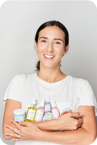 Woman smiling while holding Earth
Harbor skincare bottles in her arms.​