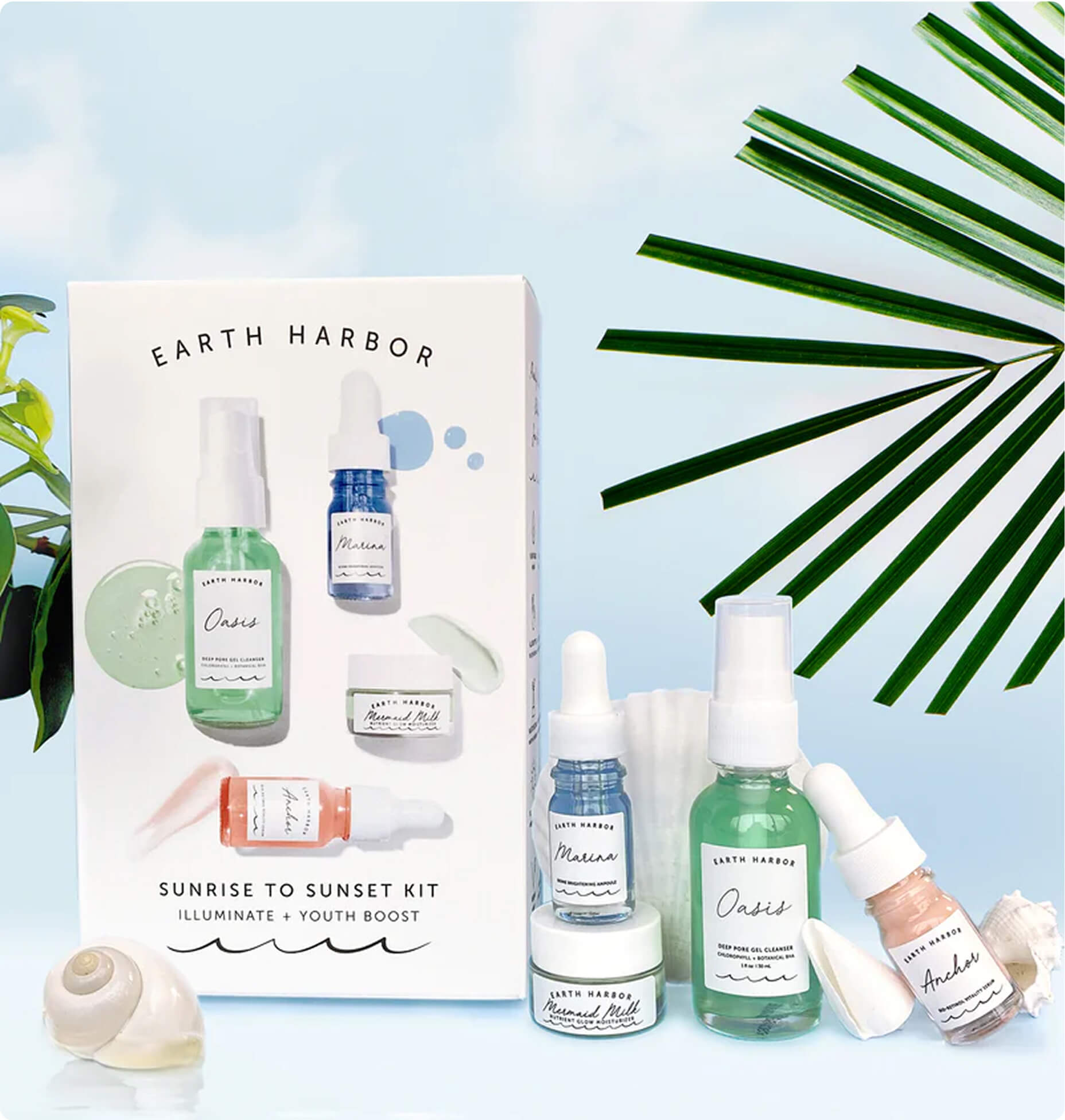 Earth Harbor Sunrise to Sunset skincare gift set box arranged next to the matching serum bottles and green
palm leaves.​
