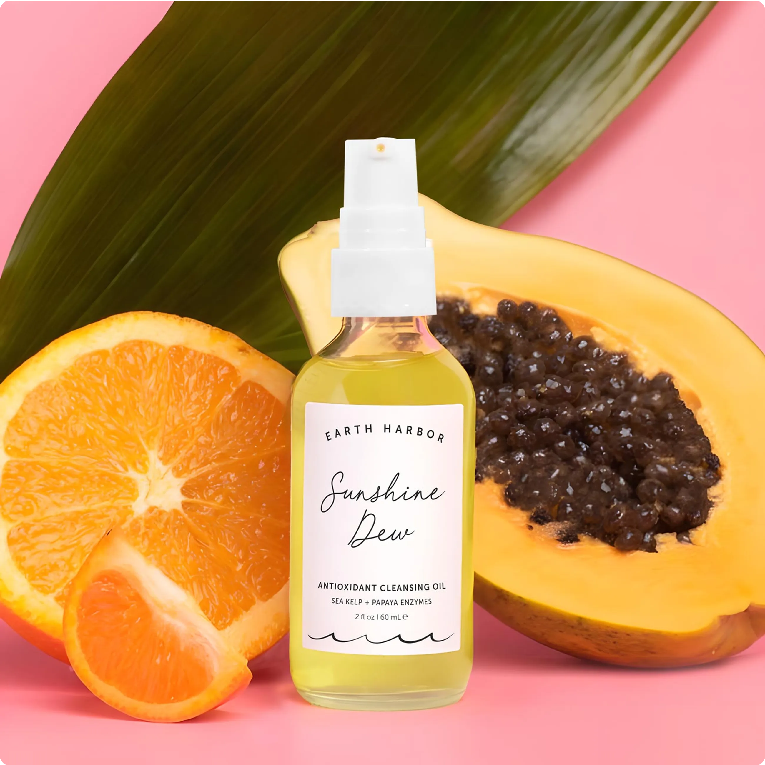 Close-up of Earth Harbor Sunshine Dew
Cleansing Oil with fresh orange slices and a
halved papaya.​