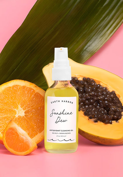 Sunshine Dew bottle displayed with
papaya, orange slices, and a green leaf.​