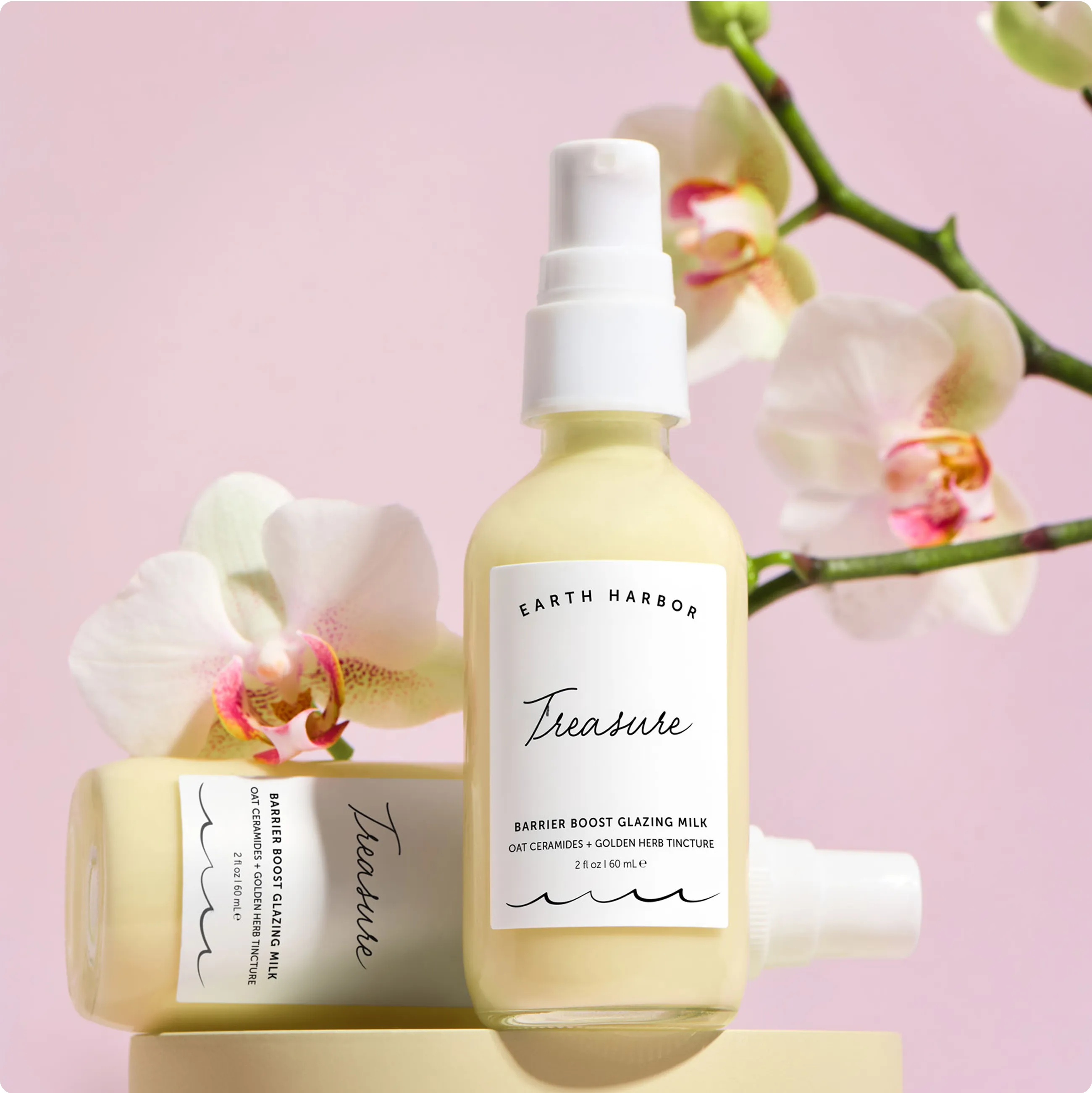 Two yellow Earth Harbor Treasure bottles
surrounded by white and pink orchid
flowers on a light pink background.​