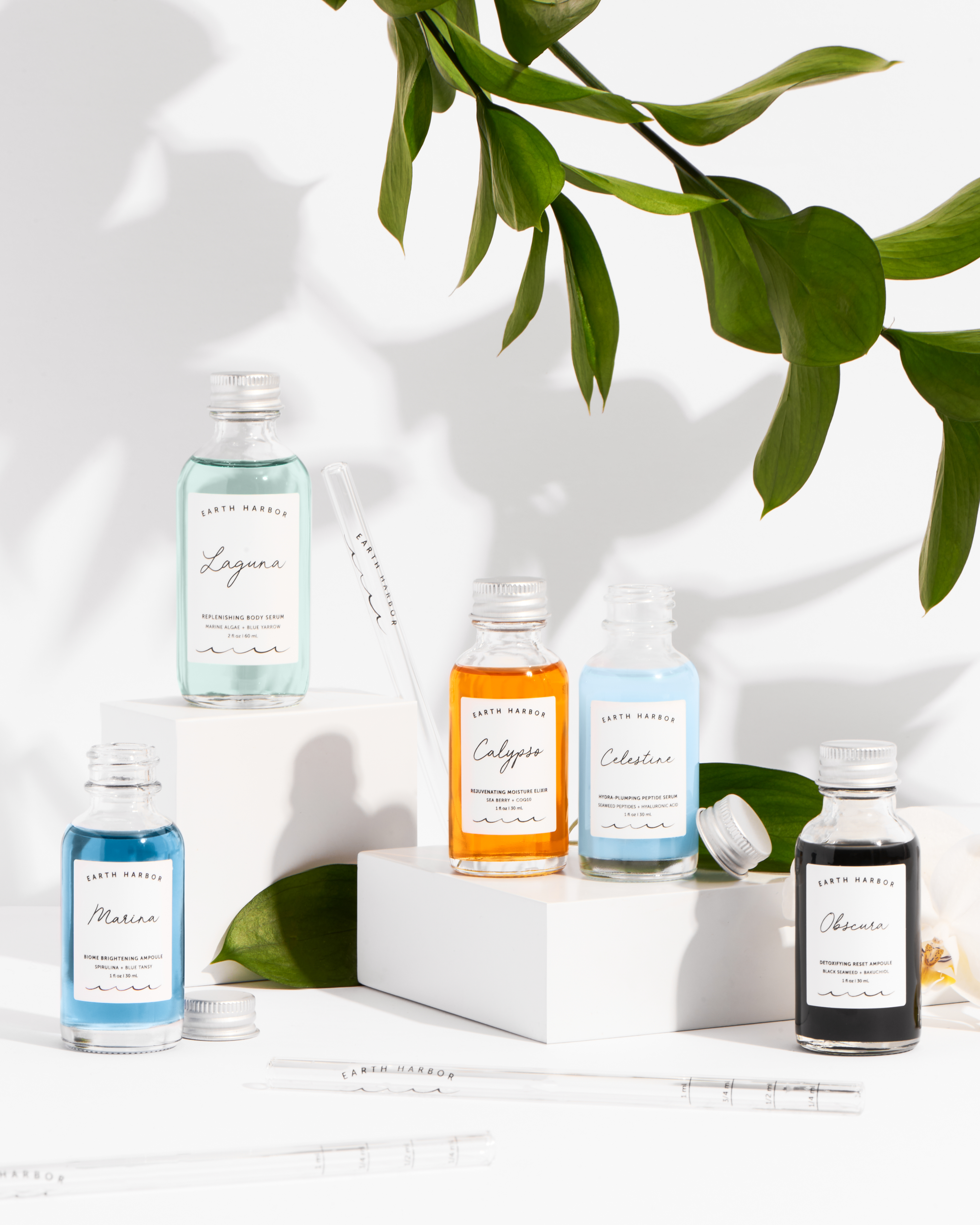 Skincare bottles displayed on white blocks
with green leaves and natural lighting.