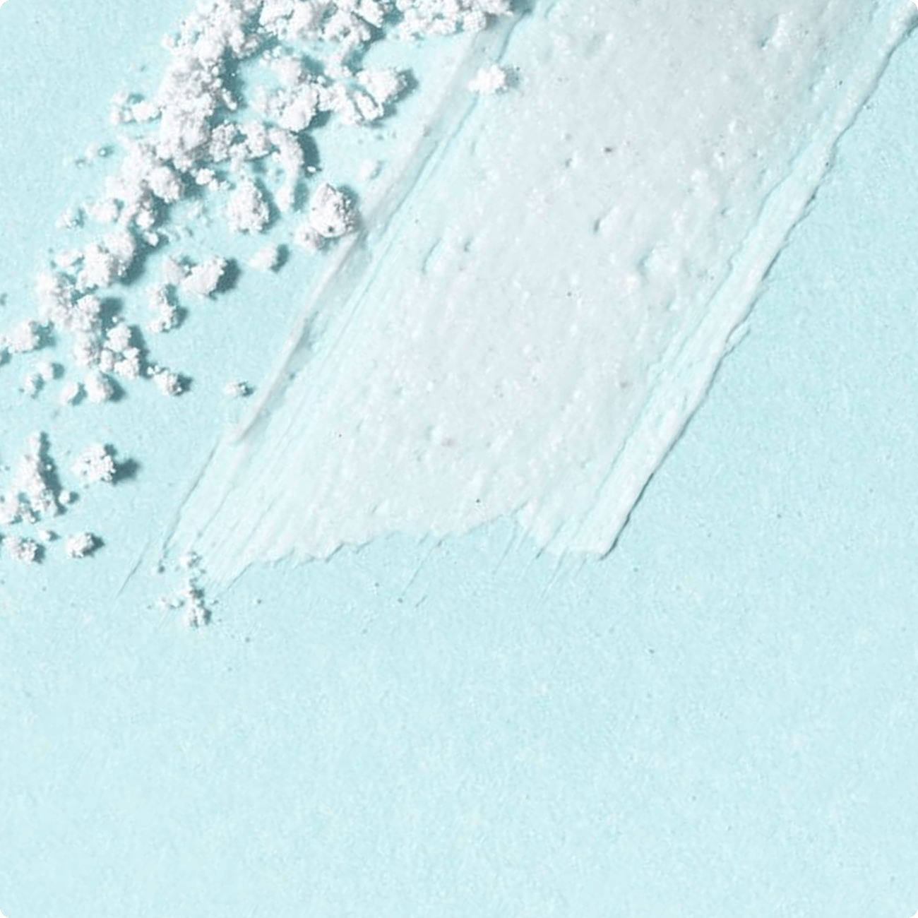 White skincare cream smear with powder
texture on a soft blue background.​